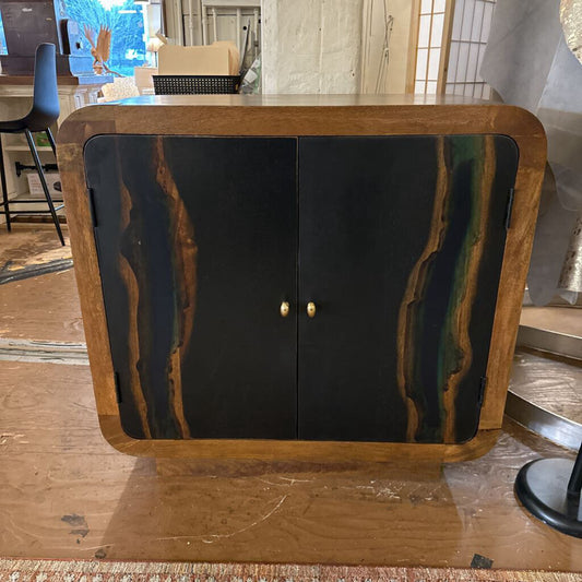 Wooden cabinet with black doors and gold handles in a room setting