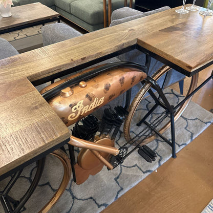 Wooden tables arranged in a U-shape with an old-fashioned Indian motorcycle seat in the center.