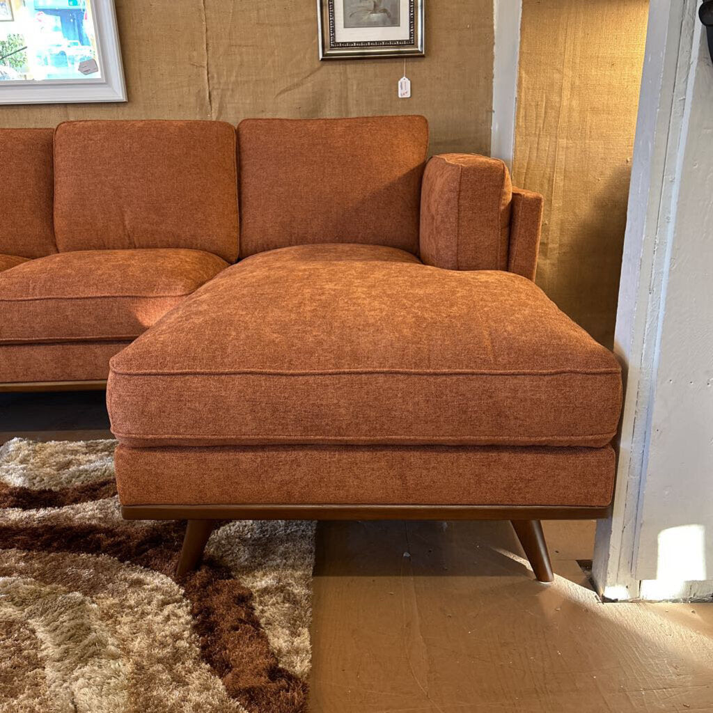 Brown sectional sofa in a room with a textured wall and rug.