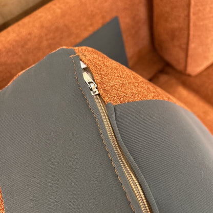 Close-up of a zipper on a gray and orange fabric surface