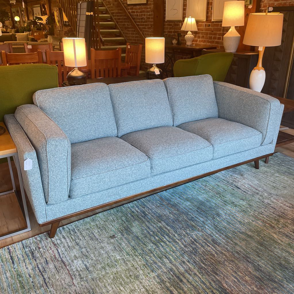 Gray sofa in a room with lamps and chairs
