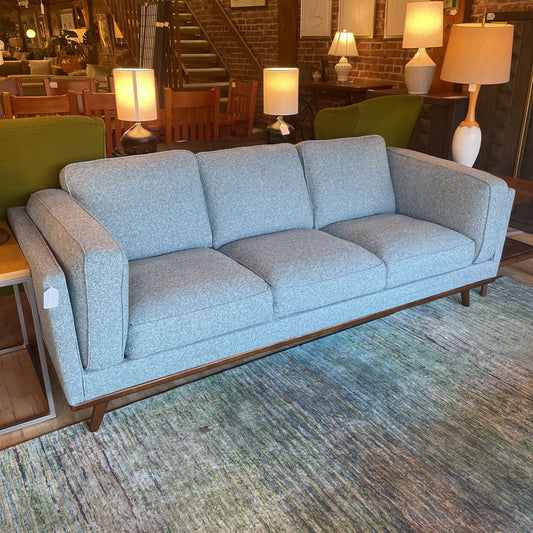 Gray sofa in a room with lamps and chairs