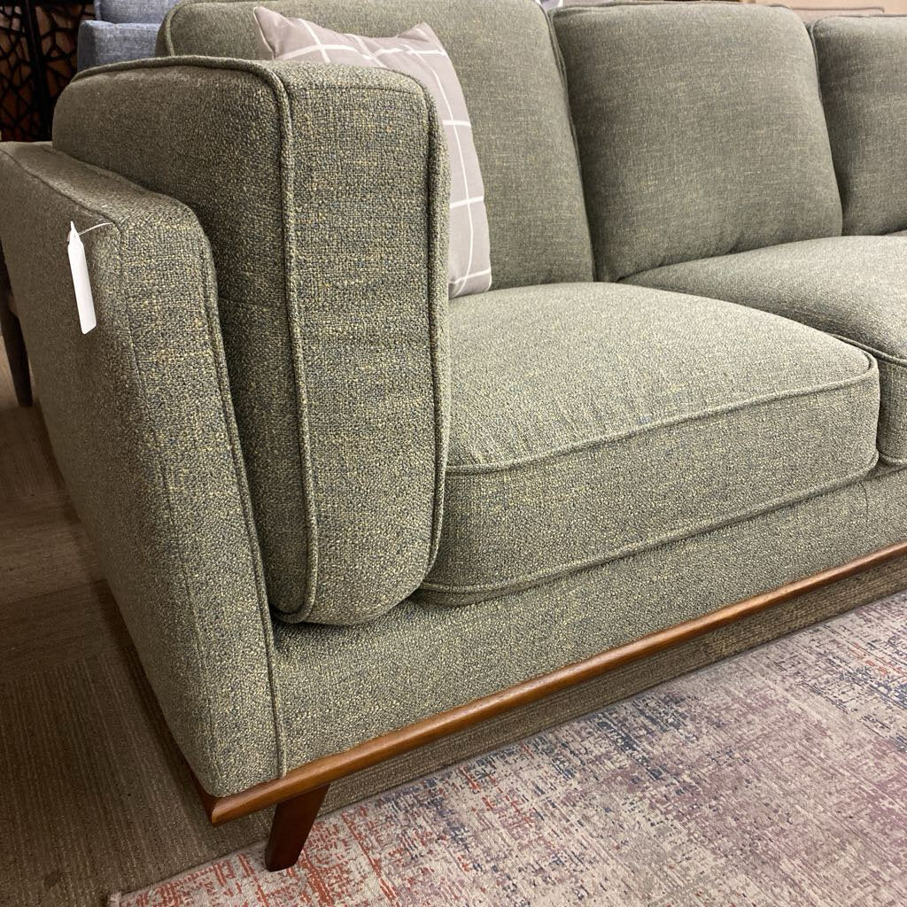 Green fabric sofa with wooden legs on a patterned rug