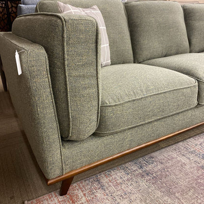 Green fabric sofa with wooden legs on a patterned rug