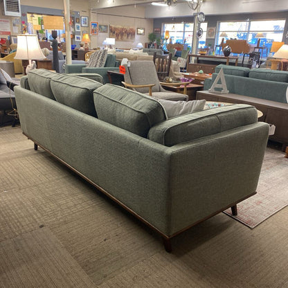 Gray sofa in a showroom with other furniture and decor items.