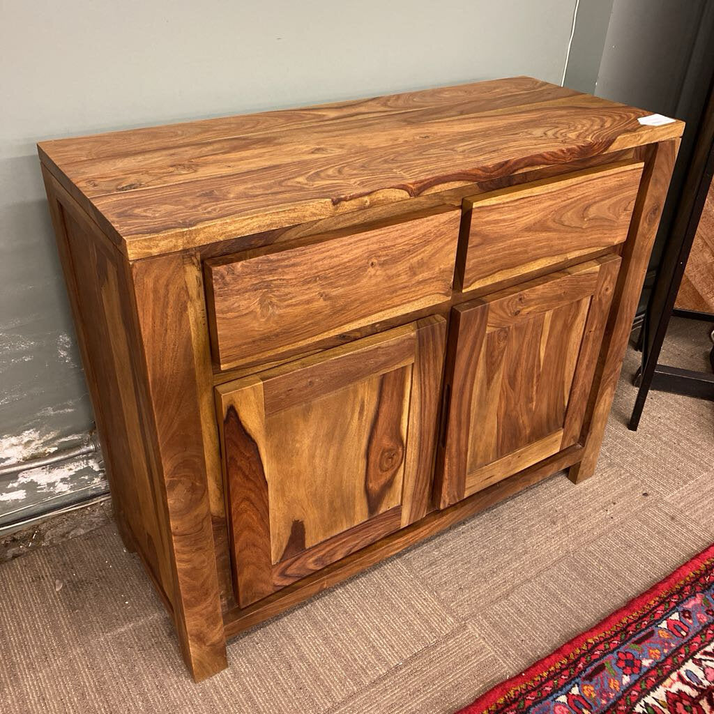 Wooden sideboard with drawers and doors against a plain wall.