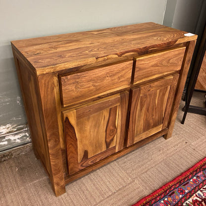 Wooden sideboard with drawers and doors against a plain wall.