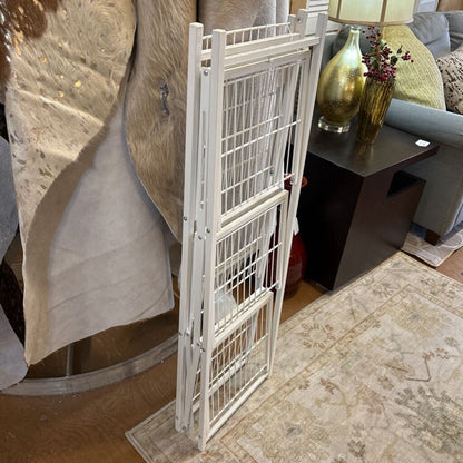 White metal pet gate in a living room setting with furniture and decor.