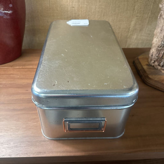 Metal storage box on a wooden surface with a textured background