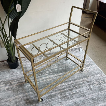 Gold bar cart with glass shelves on a gray rug