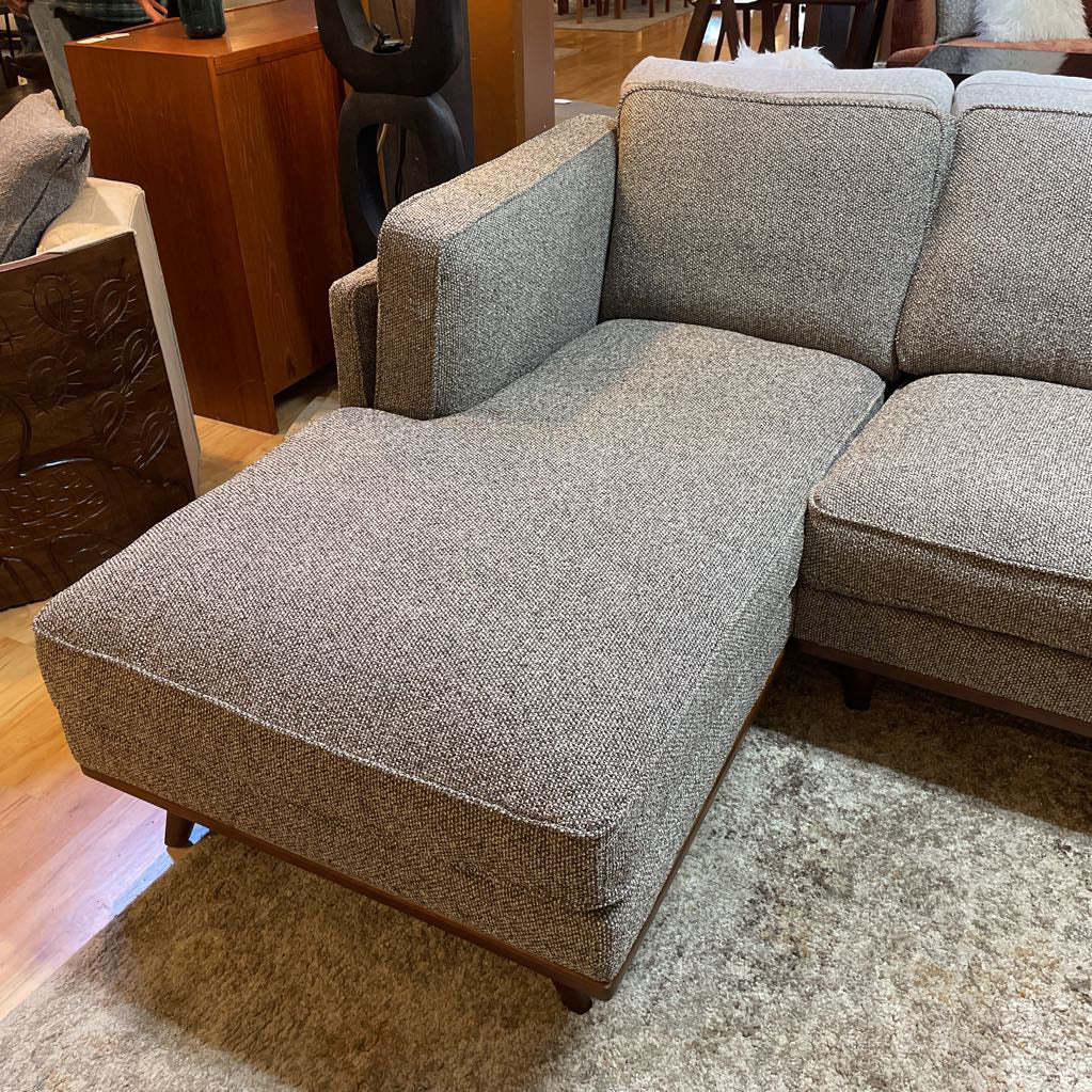 Gray textured sectional sofa in a room with wooden furniture.