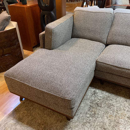 Gray textured sectional sofa in a room with wooden furniture.