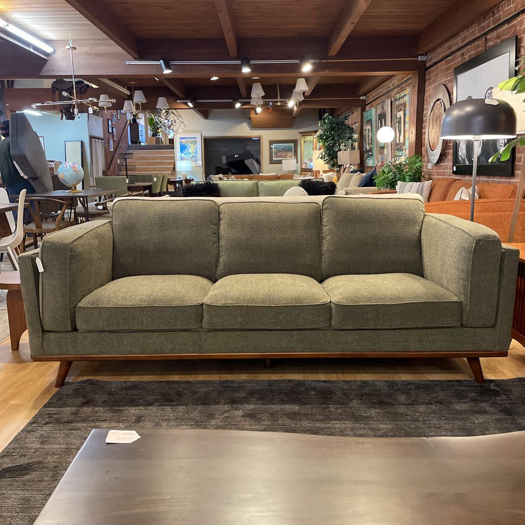Green sofa in a room with wooden floors and exposed beams