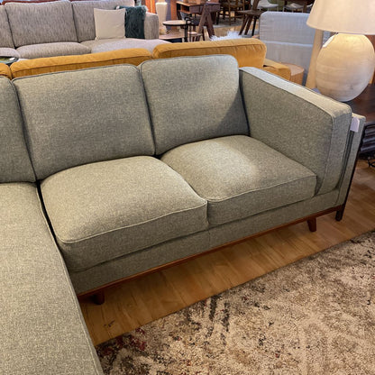 Gray sectional sofa in a showroom setting with other furniture.