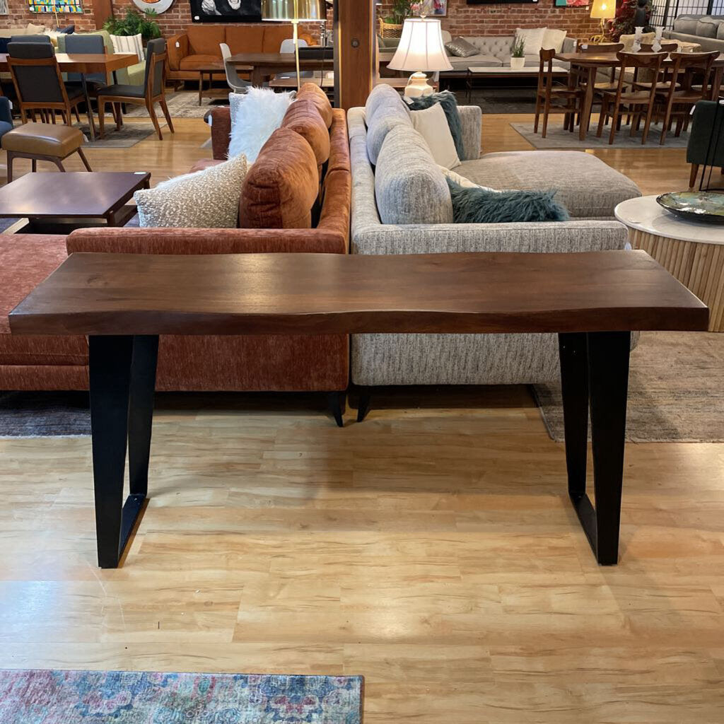 Wooden coffee table in front of a sofa with a store interior in the background
