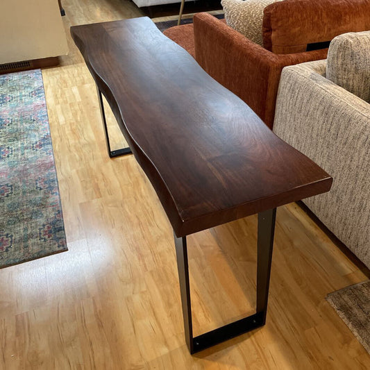 Wooden bench in a living room setting with a sofa and rug.