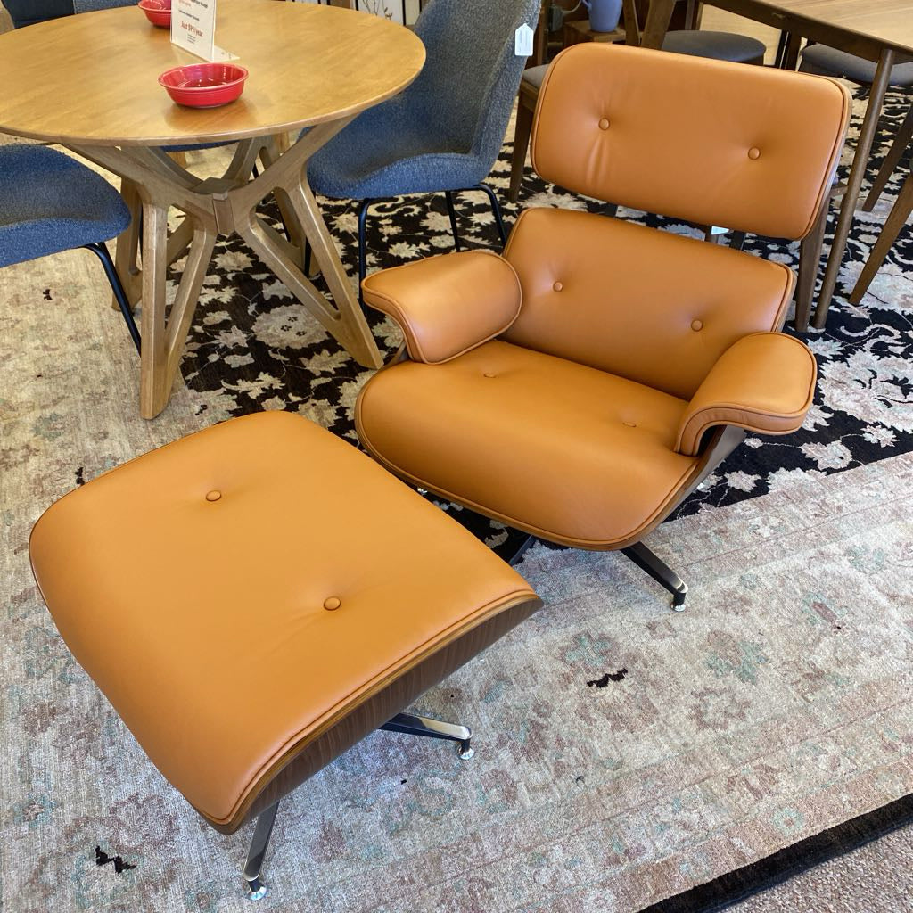 Brown leather chair and ottoman on a patterned rug with a table and chairs in the background.
