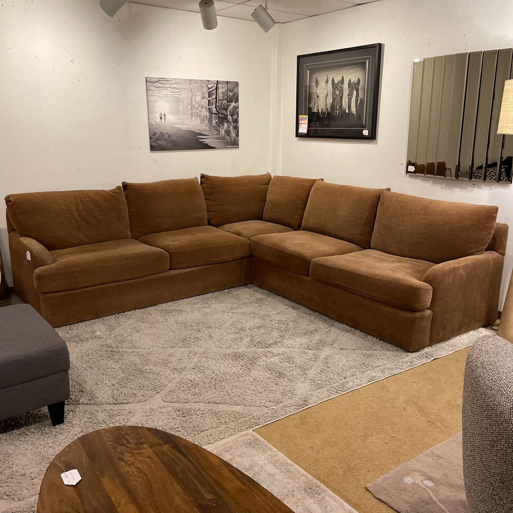 Brown sectional sofa in a room with a rug and wall art