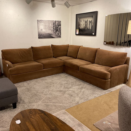 Brown sectional sofa in a room with a rug and wall art