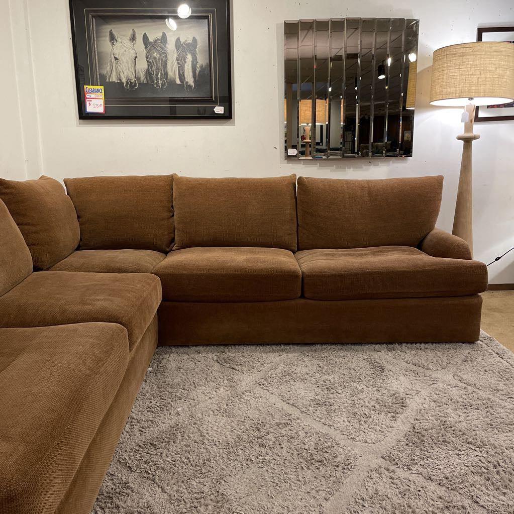 Brown sectional sofa in a living room setting with decor elements.