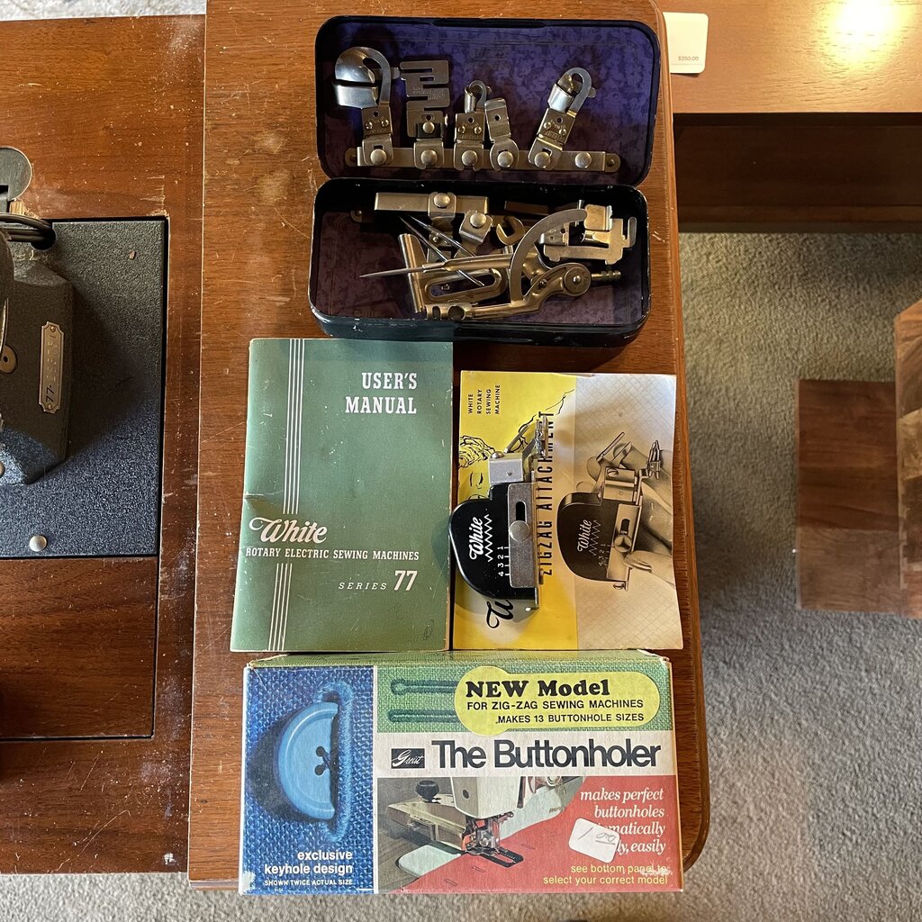Collection of vintage sewing machine parts and manuals on a wooden surface.