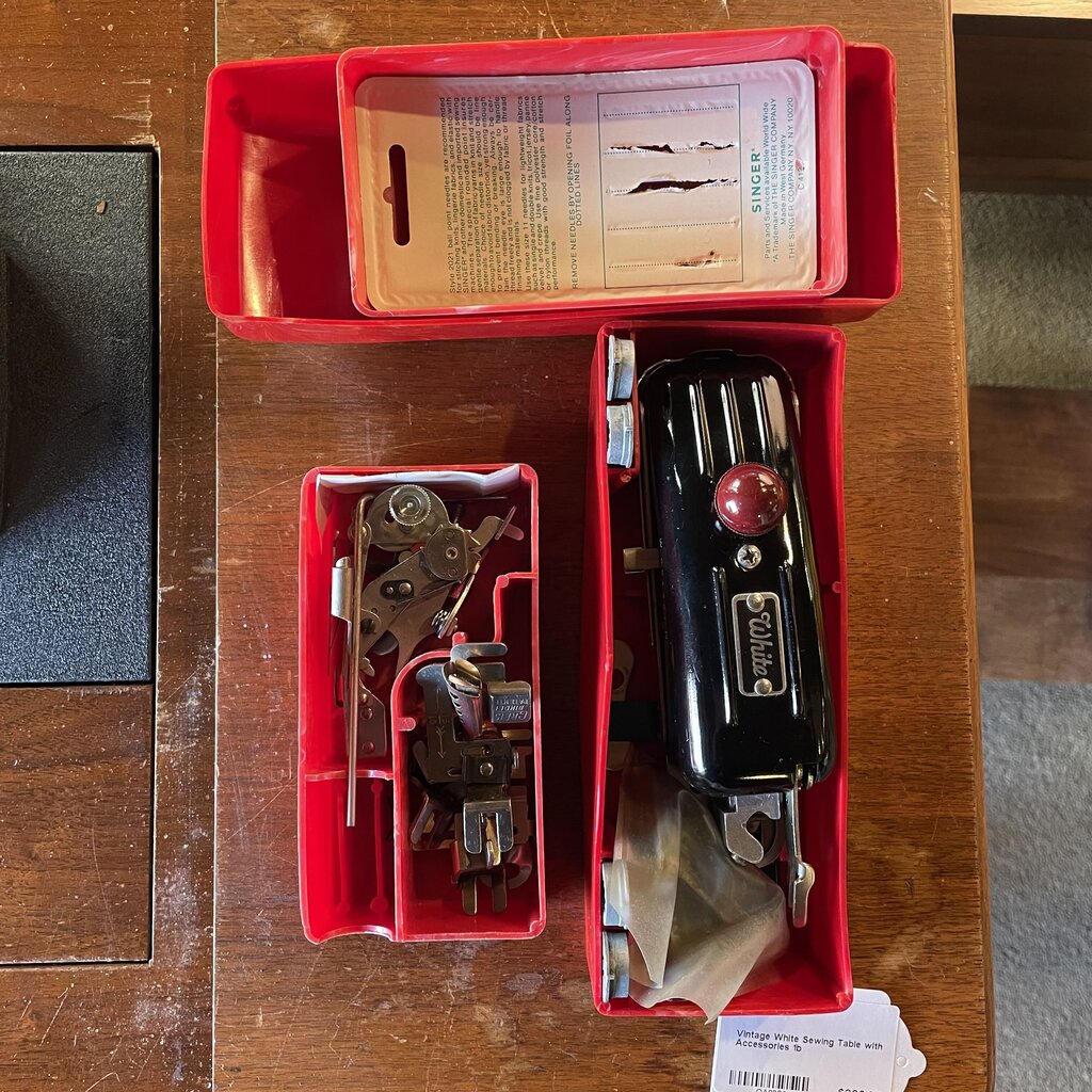 Vintage sewing machine parts in a red toolbox on a wooden surface