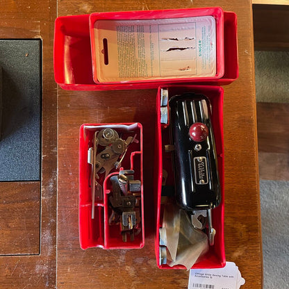 Vintage sewing machine parts in a red toolbox on a wooden surface