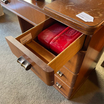 Wooden drawer with a red container inside, on a carpeted floor.