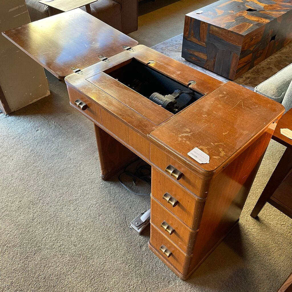 Vintage wooden desk with open top and drawers on a carpeted floor.