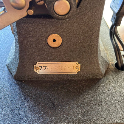 Close-up of a textured brown object with a gold tag displaying numbers on a gray surface.