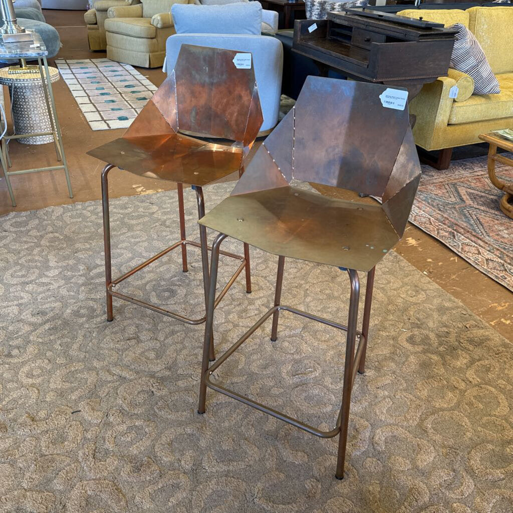 Two metal bar stools with a textured surface in a room with furniture and decor.