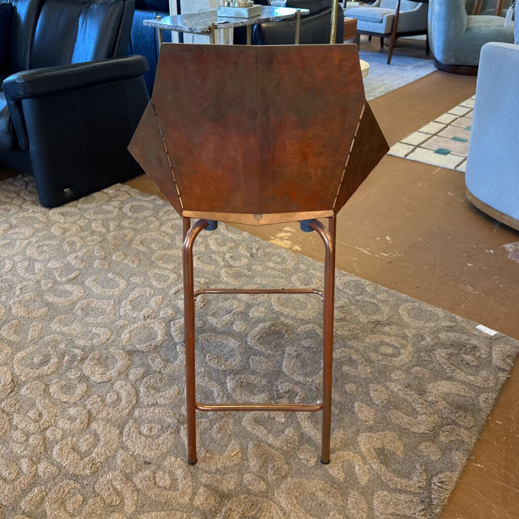 Bronze bar stool on a patterned carpet with furniture in the background