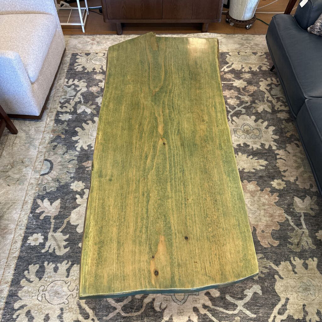 Large green wooden board on a patterned rug in a living room setting