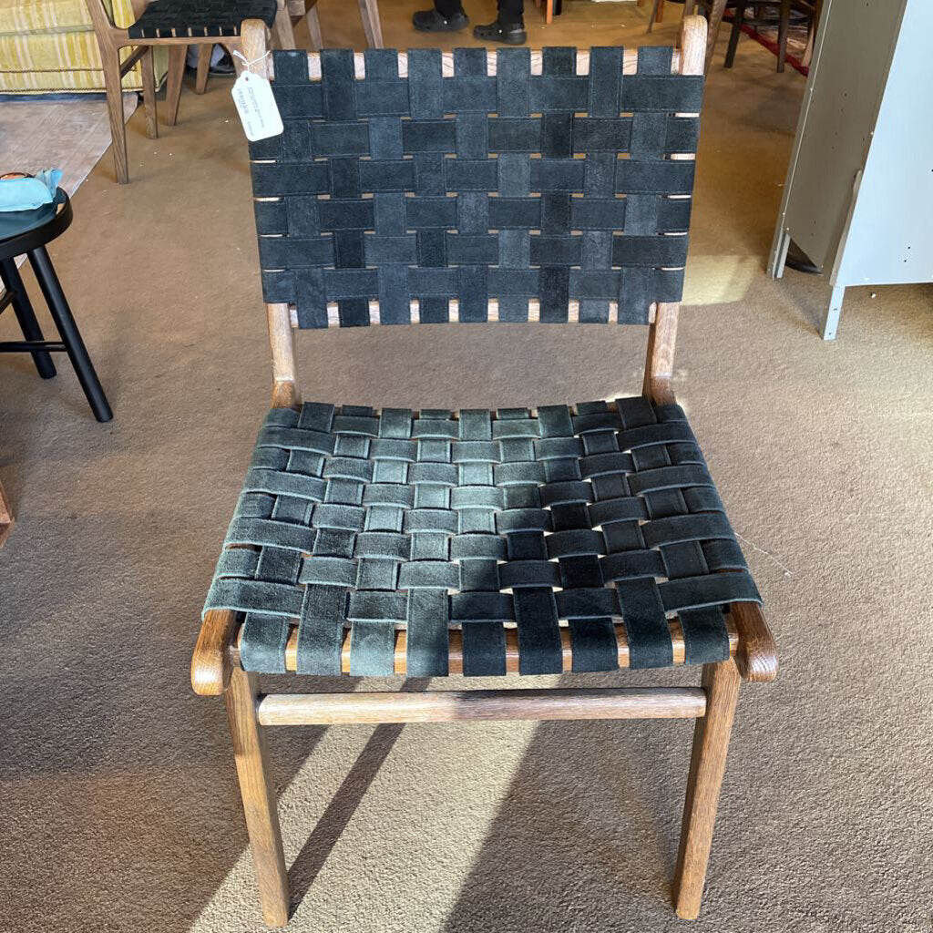Chair with woven black strap seat and backrest on a carpeted floor.