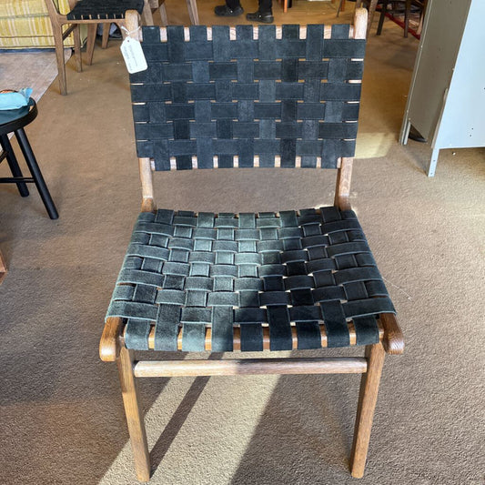 Chair with woven black strap seat and backrest on a carpeted floor.