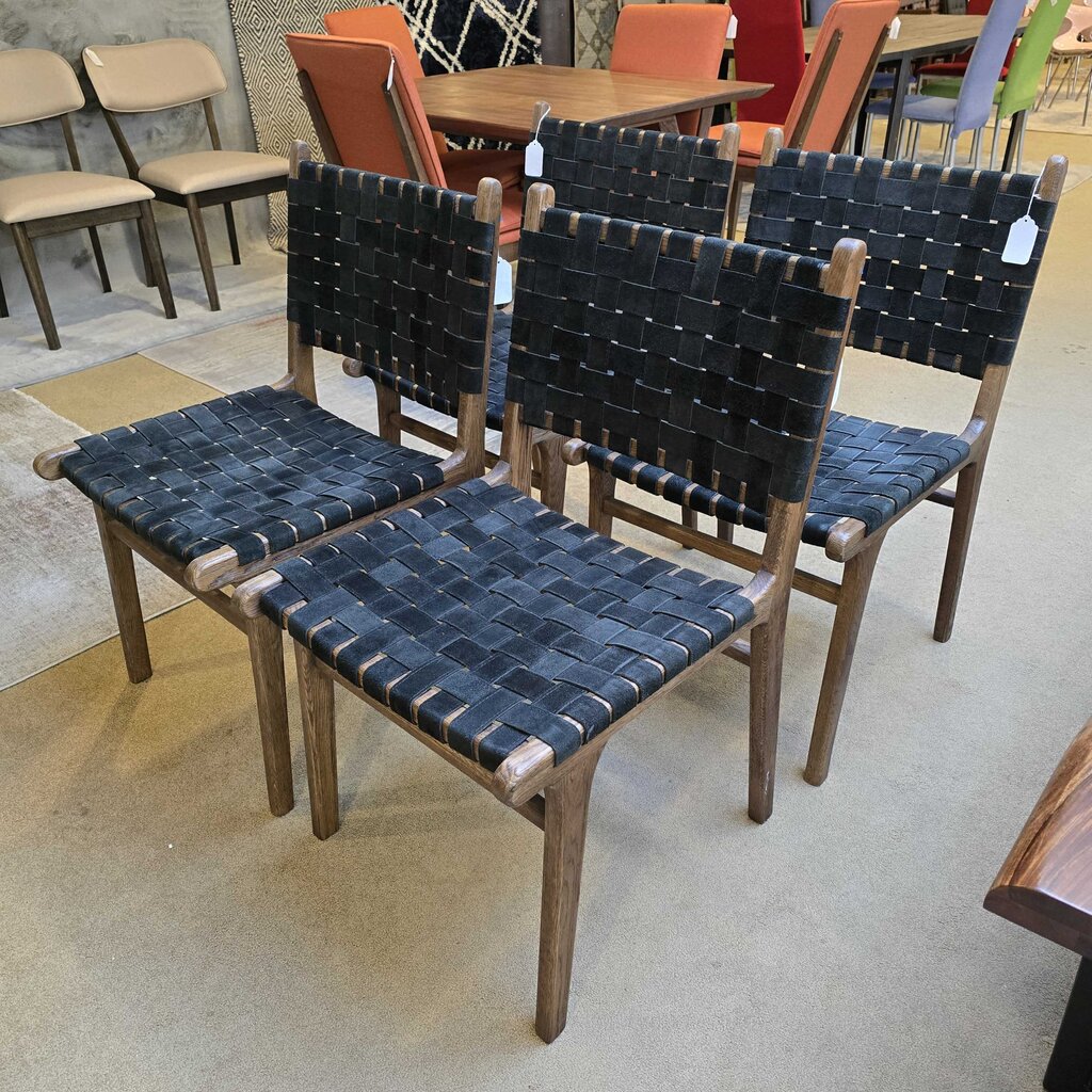 Set of four woven chairs with dark blue seats and backrests in a showroom setting.