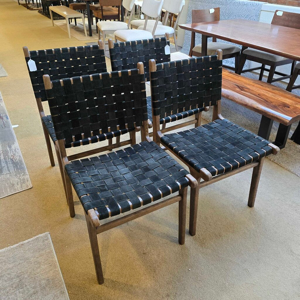 Two black woven chairs with wooden frames on a beige floor.