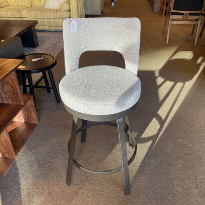 Gray bar stool with a textured seat in a furniture store setting