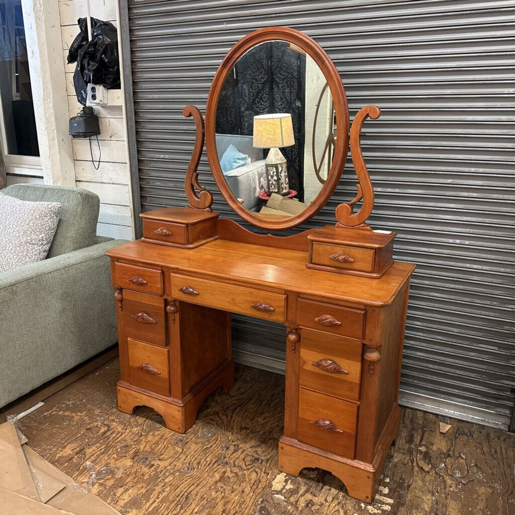 Wooden vanity with mirror on a wooden floor against a metal shutter.