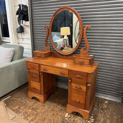 Wooden vanity with mirror on a wooden floor against a metal shutter.