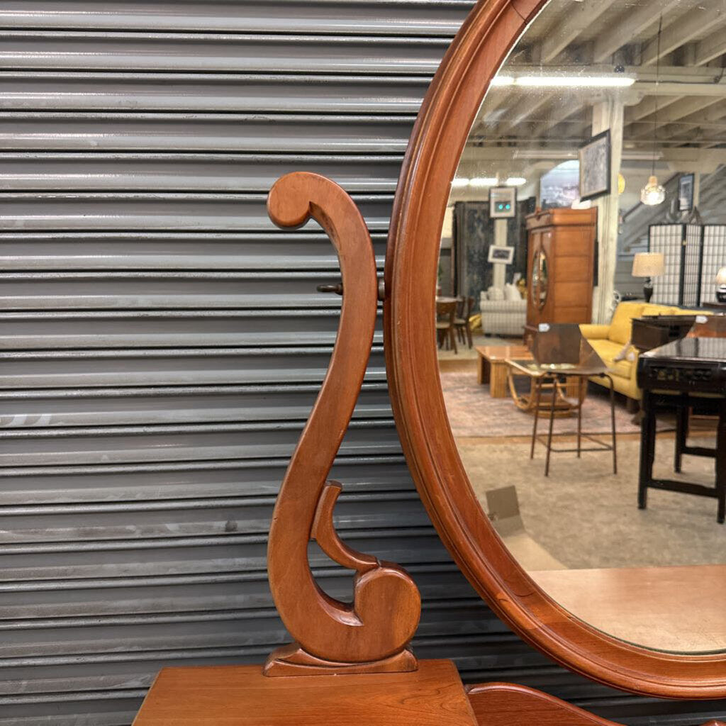 Wooden oval mirror with decorative frame in a showroom setting