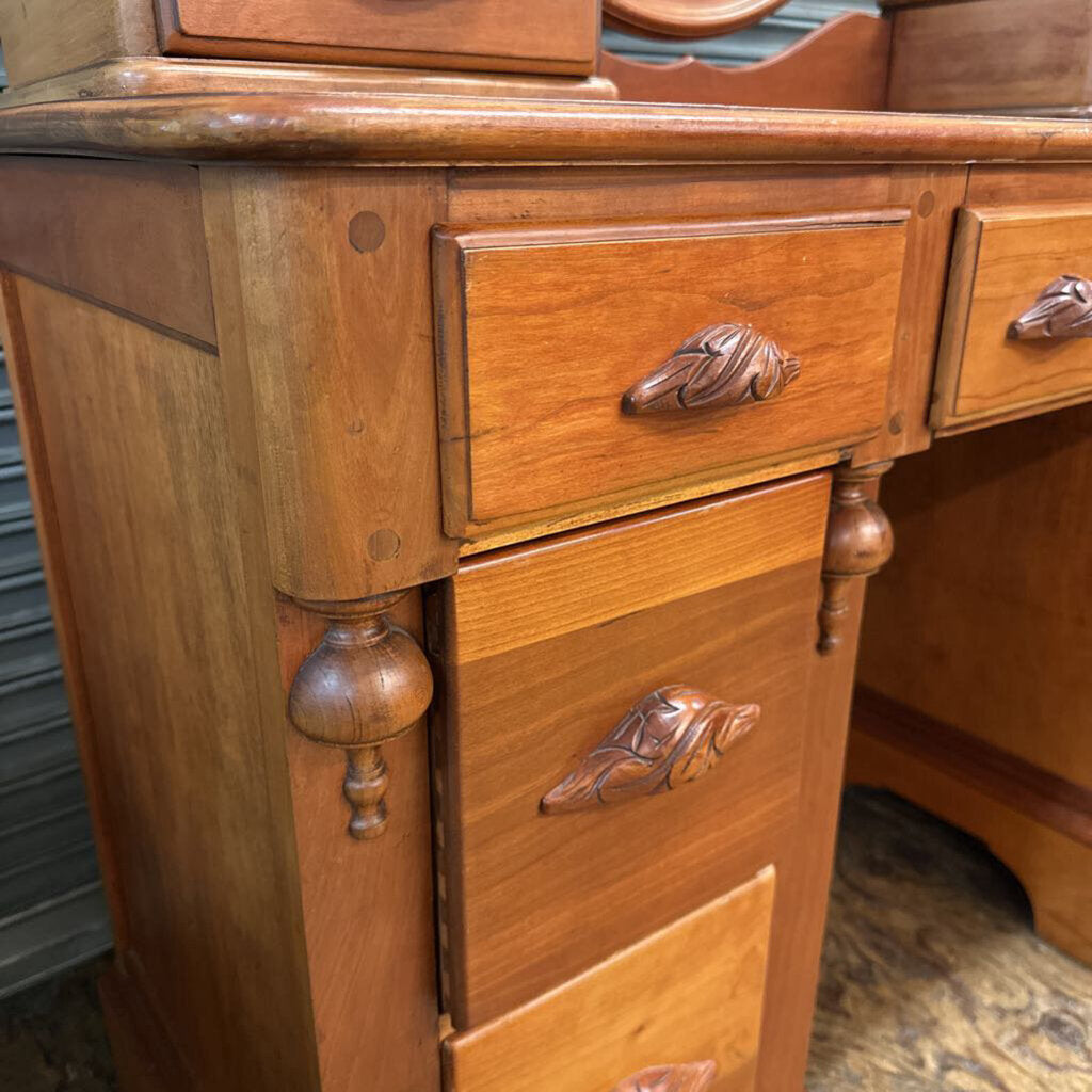 Close-up of a wooden desk with ornate handles on drawers.