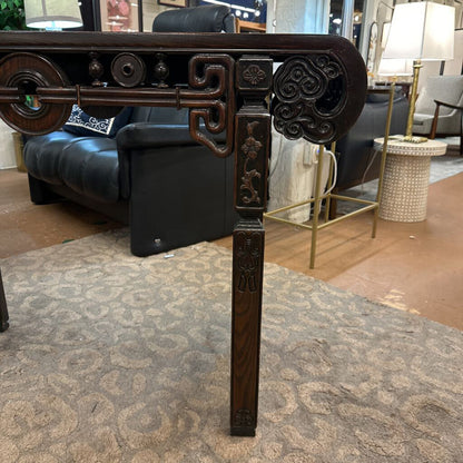 Decorative wooden table leg with intricate carvings in a room setting.