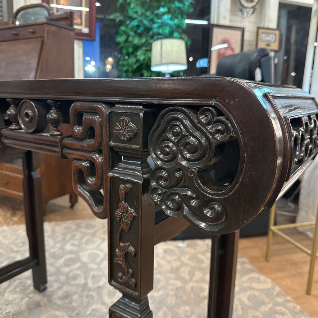 Decorative wooden table with intricate carvings in a room setting.