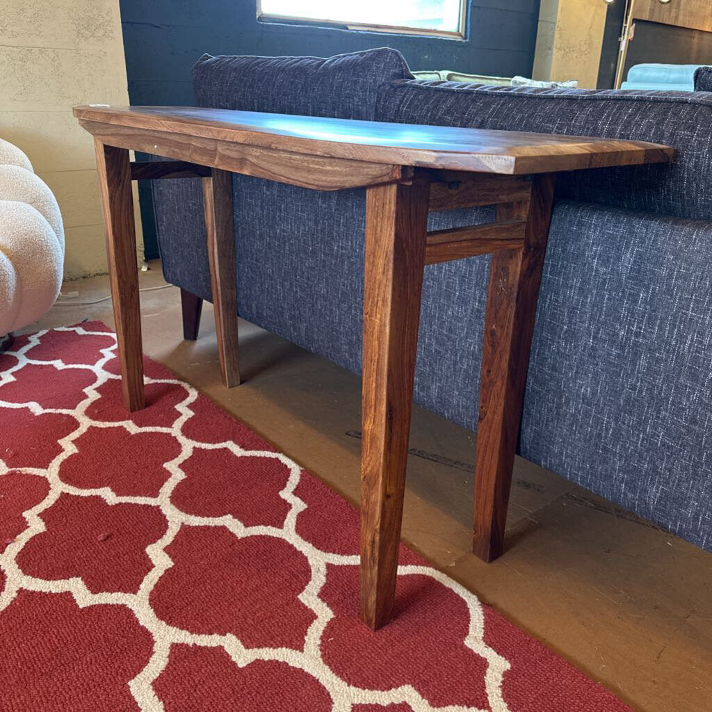 Wooden table in a room with a blue sofa and red patterned rug