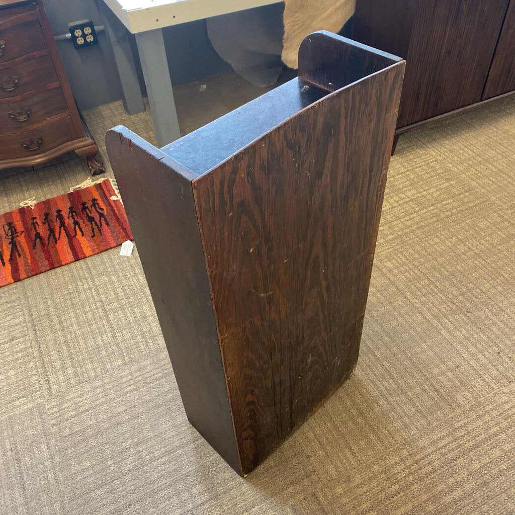 Wooden bookshelf against a carpeted floor with furniture in the background