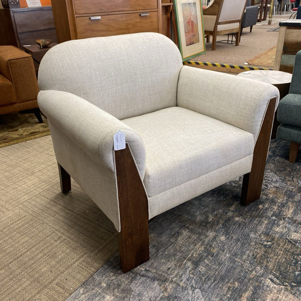 Beige armchair with wooden legs in a furniture store setting