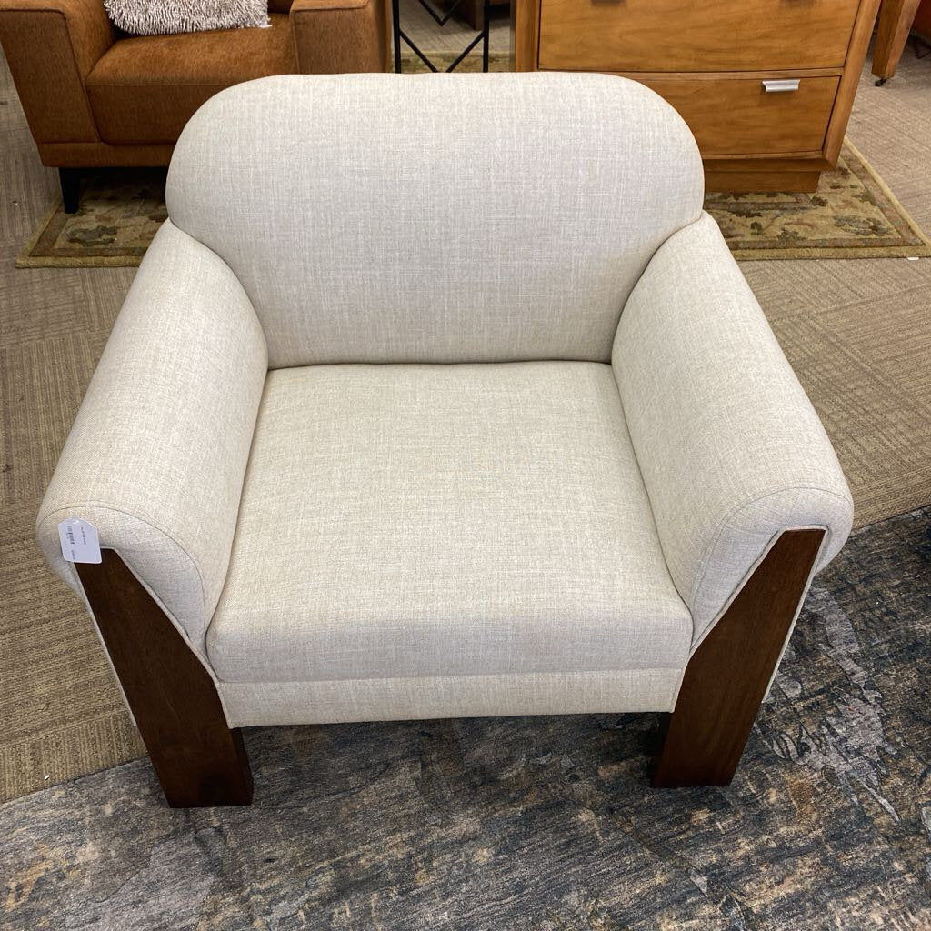 Beige armchair with wooden legs on a carpeted floor