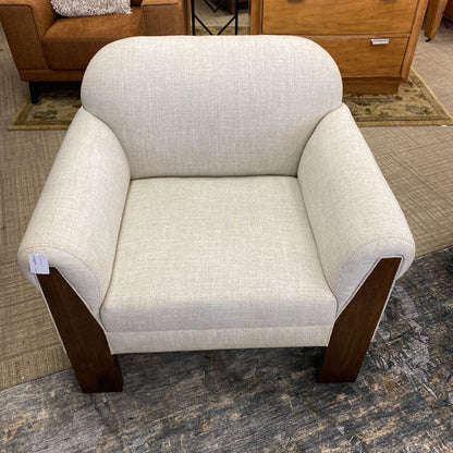 Beige armchair with wooden legs on a carpeted floor
