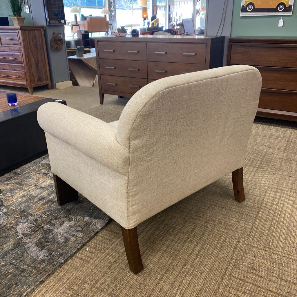 Beige armchair with wooden legs in a furniture store setting
